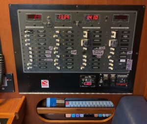 boat breaker panel with columns of switches and 4 lcd meters at the top of each column. the breaker panel is labeled with standard labels as well as washi tape labels for clarifications