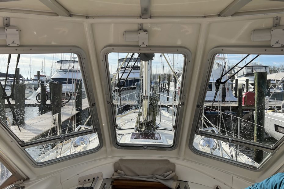 view from the cockpit, looking forward over the foredeck. the mast is in view as well as lots of lines. in the background are several large motorboats