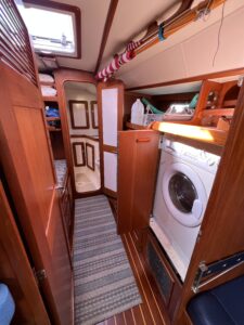 looking forward into the forward cabin. the washer/dryer combo unit is on the right, and the head is at the other end of the room. there is teak everywhere.