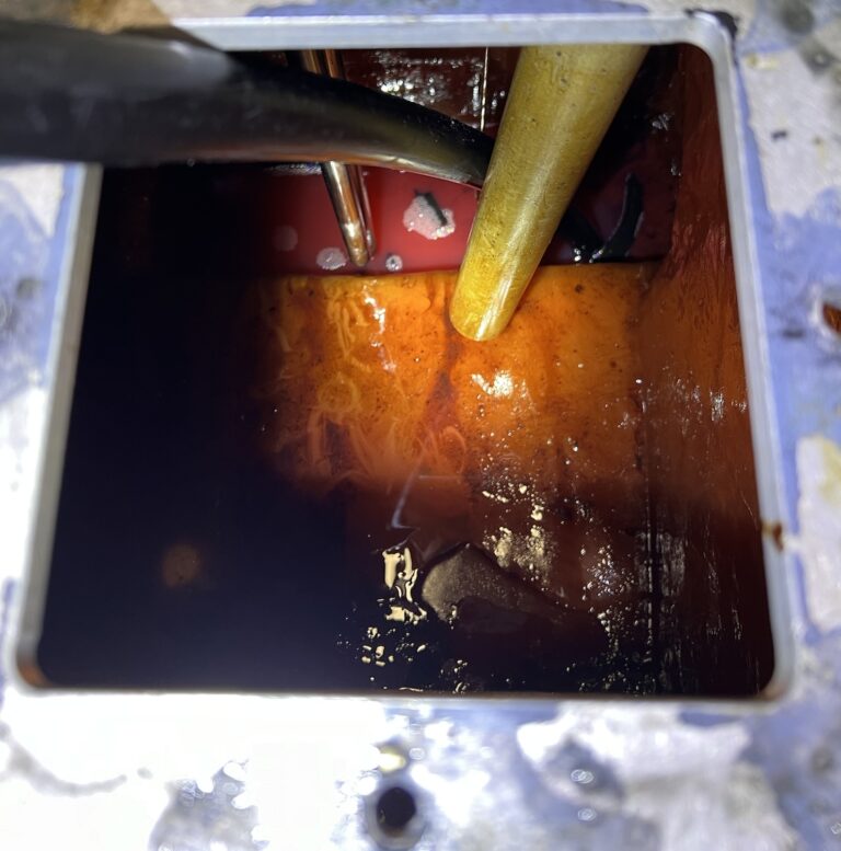 looking down into a diesel tank through the open inspection port. it's pink and orange, with some black blobs of biomasses