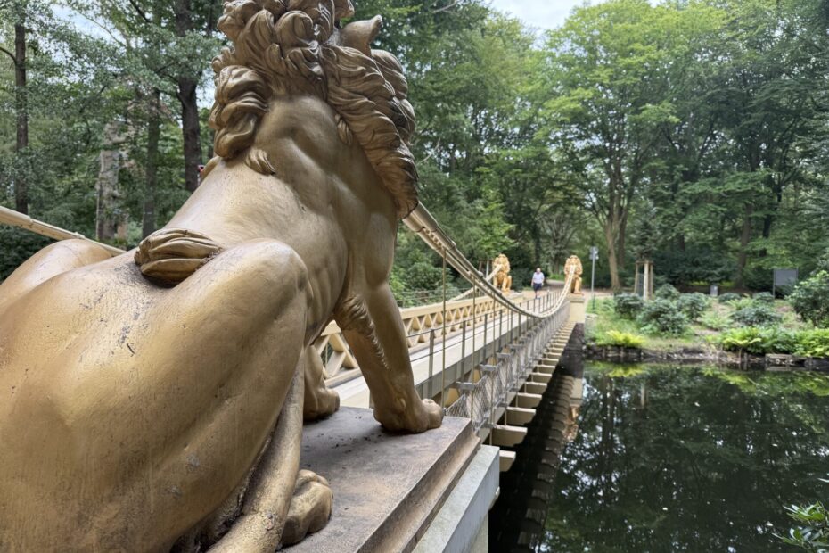 A golden bridge in a park with lions at each end